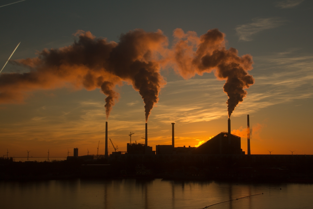 A low angle shot of a factory with smoke and steam coming out of the chimneys captured at sunset